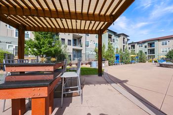 A wooden table and chair set under a wooden roof.